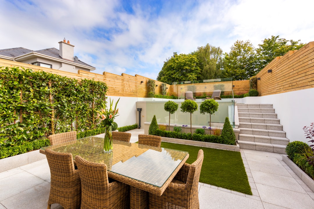 a patio with a table and chairs next to a fence - Foto de Tile Merchant Ireland en Unsplash